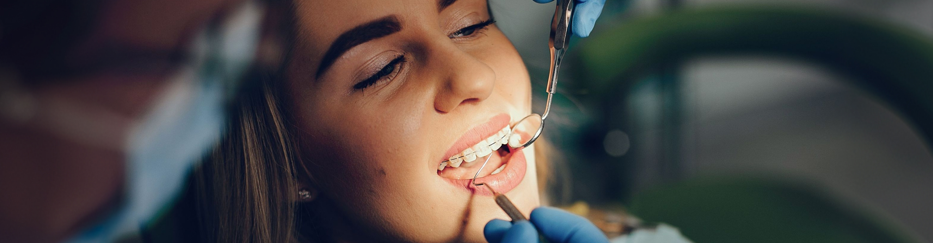 Patient with clear ceramic braces undergoing an orthodontic evaluation at a dental appointment.